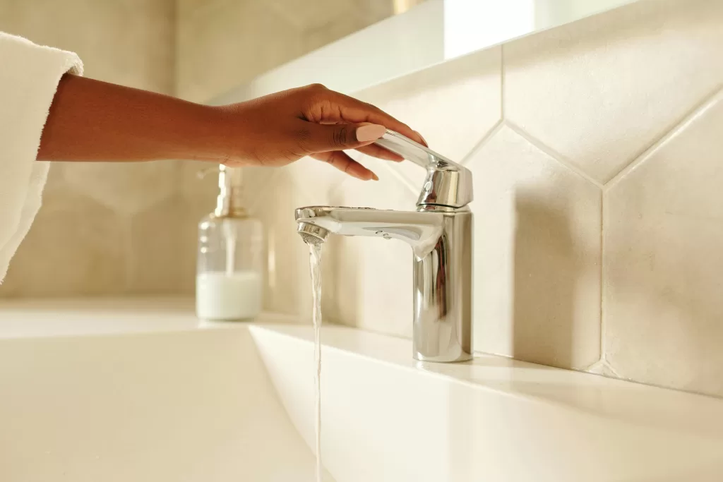 A hand turning on sink water