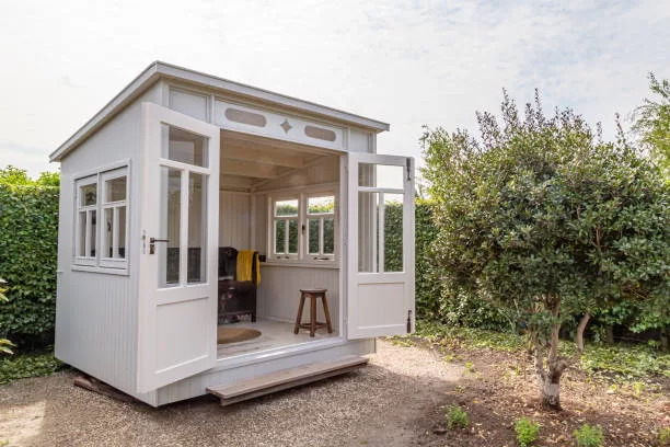 Sunny white wooden she-shed between trees
