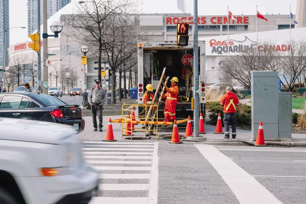 Workers surrounded by cones at a busy intersection