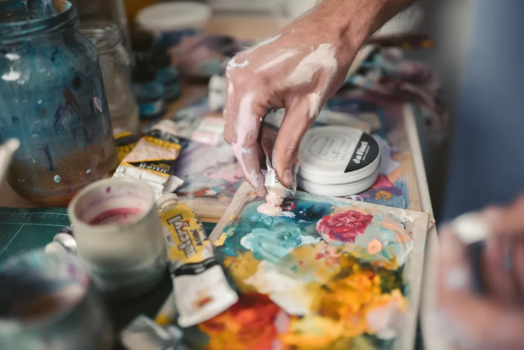 Persons Hand using textured paints, squuezing out of bottle