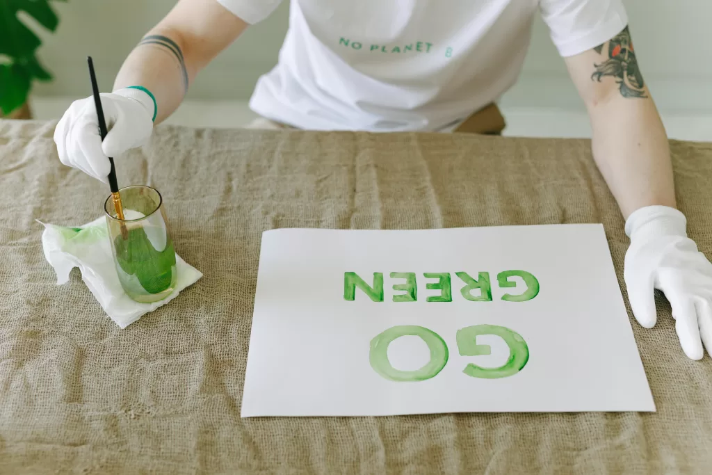 Person painting Go Green on papaer