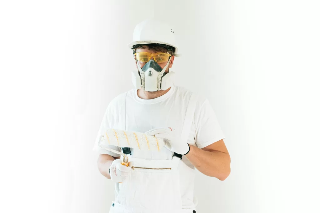 Professional painter holding paint bruish wearing mask
