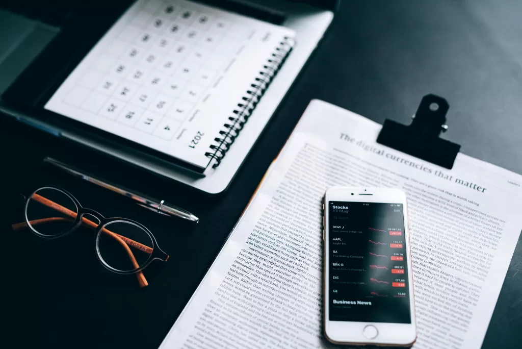 Calendar with article, cellphone, glasses and pen on desk