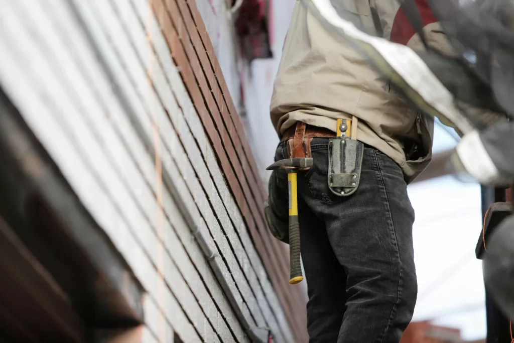 Worker standing next to house wearing tool belt