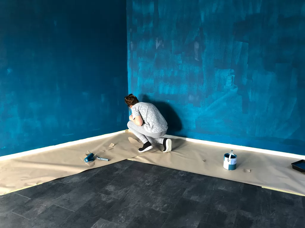 person putting down protector of floors to paint