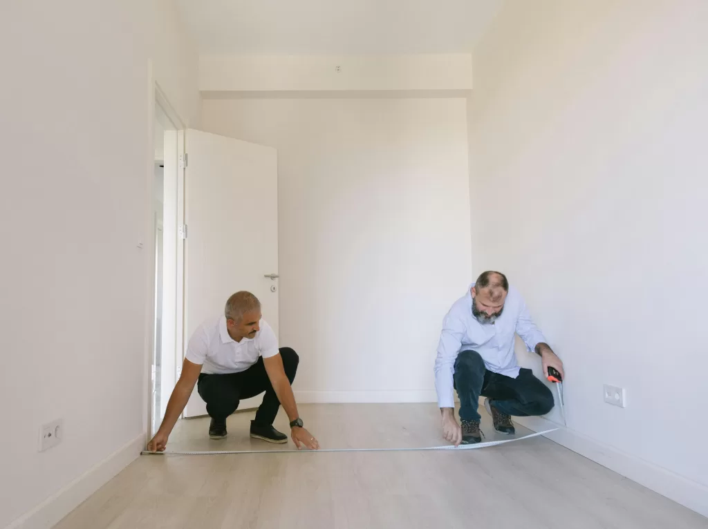 Two Men measuring the room before renovation