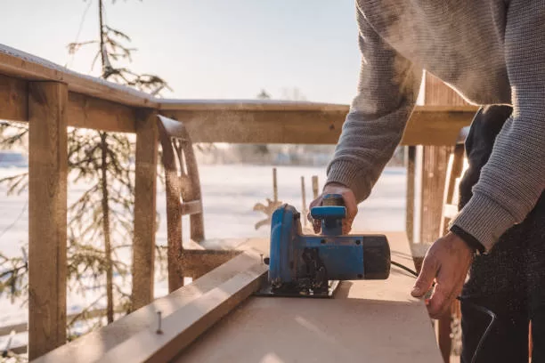 Man sawing wood for home improvement carpentry  outdoors in cold winter