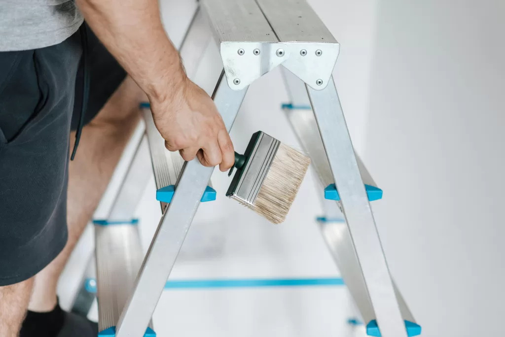 man on ladder preparing to paint