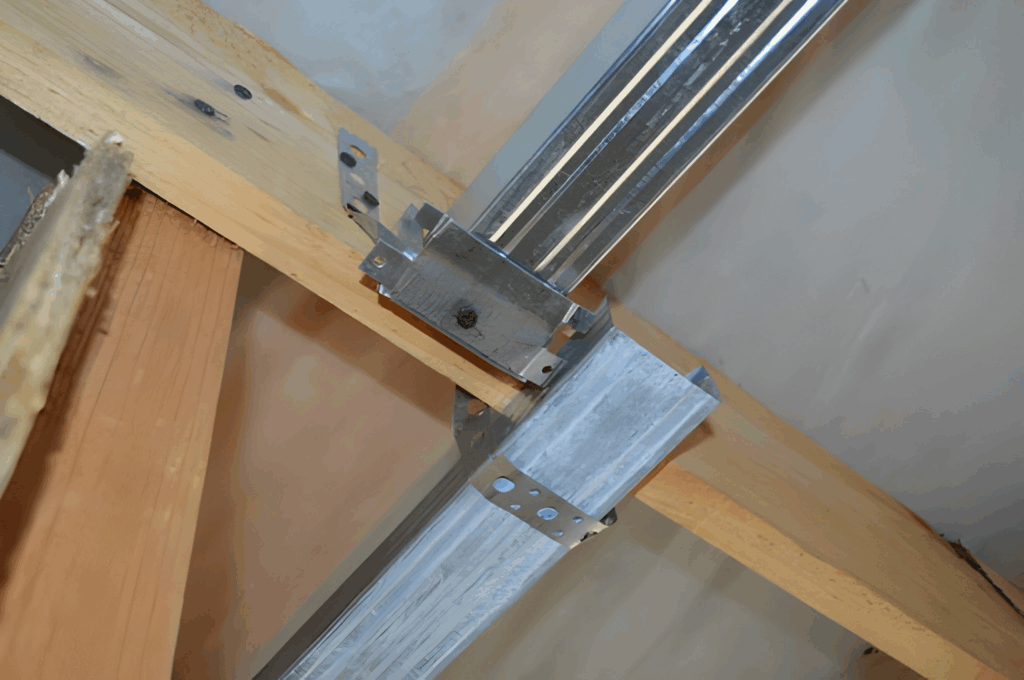 Hat channel on sound isolation clips installed before a basement drywall ceiling.