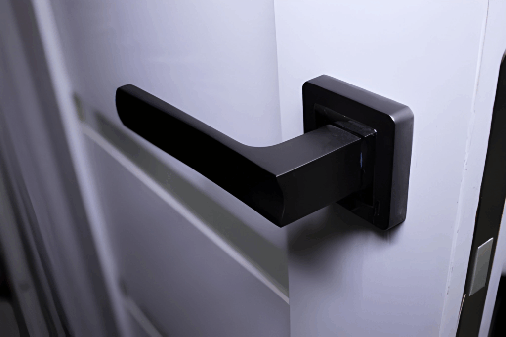 Matte black door lever with a square rosette installed on a painted interior door.