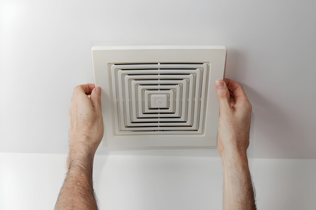 Close up of a modern bathroom exhaust fan installed in a white ceiling.