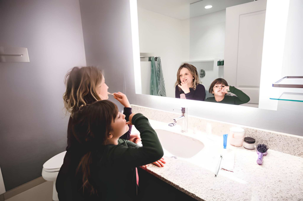 Two kids brushing their teeth at a shared bathroom vanity.
